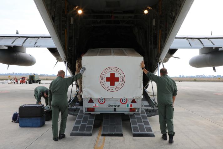 A truck with goods being loaded in the back of a plane.